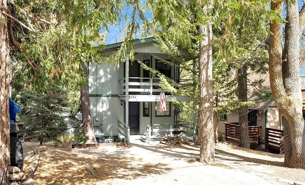 Two-story mountain home with balcony and American flag among tall cedars at 2434 Fir Drive, Running Springs