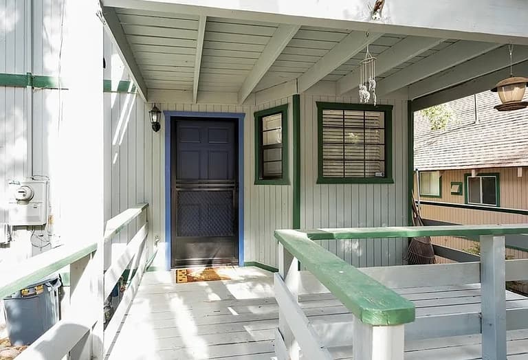 Covered front porch with blue-trimmed entry door and green railings at 2434 Fir Drive