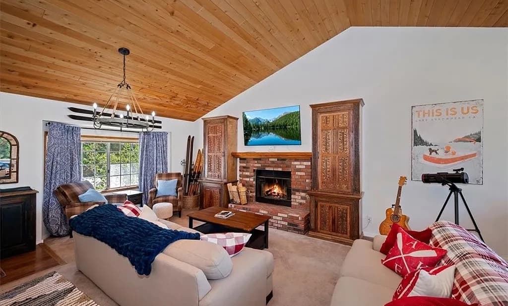 Living room with cathedral wood ceiling, wagon-wheel chandelier, and cozy seating at 27398 Matterhorn Drive